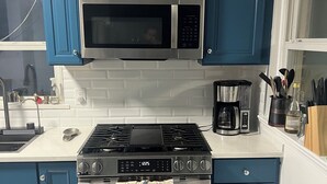 A kitchen with blue cabinets, a stainless steel microwave, a gas stove, and a built-in oven. - Family friendly Home, 3BR, Old Town, Nat. Harbor & DC. Nice neighborhood (Alexandria)