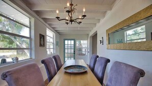 A dining area with a long wooden table, six upholstered chairs, a chandelier, large windows, and a mirror on the wall. - 3B Near Englewood Beach! Pet Friendly Sunlit Home (Englewood)