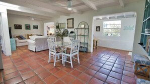A spacious living area with a tiled floor, a dining table with chairs, a sofa, and a bookshelf. - 3B Near Englewood Beach! Pet Friendly Sunlit Home (Englewood)