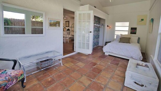 A room with a bed, a small table, and a chair. There is a door leading to another room. - 3B Near Englewood Beach! Pet Friendly Sunlit Home (Englewood)
