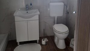 Casa de banho com lavatório branco, sanita e bidé.