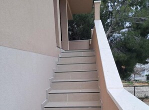 Un escalier de couleur beige menant à un palier doté d’une rampe blanche.