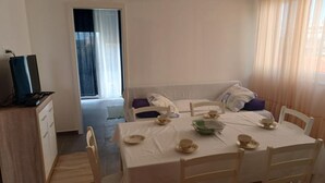 Quarto pequeno e limpo com cama, escrivaninha e mesa de jantar posta para dois.