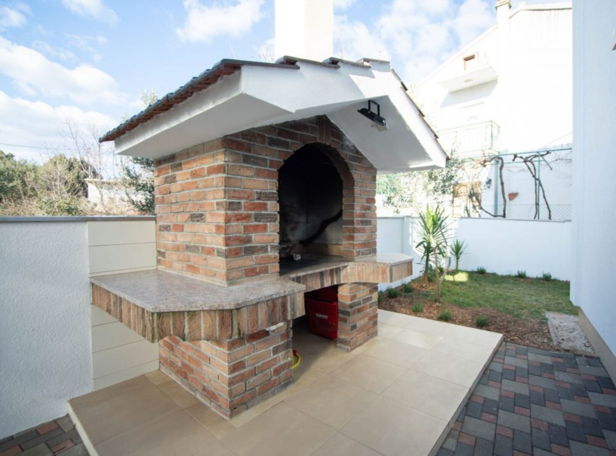 Un horno de ladrillo al aire libre con chimenea, situado en un patio empedrado.
