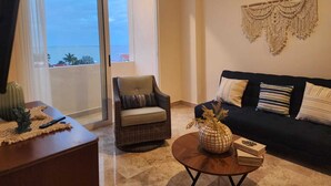 A living room with a sofa, armchair, coffee table, and a view through a sliding door to the outside. - Ocean View / Swimming pool / Wifi (Boca del Río)