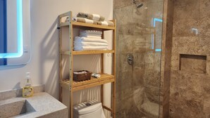 A bathroom with a glass-enclosed shower, a wooden shelf with towels, a toilet, and a soap dispenser. - Ocean View / Swimming pool / Wifi (Boca del Río)