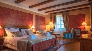 A hotel room with a large bed, a sofa, a chair, a small table, and a desk. - Jurjevec Castle - Standard room 2 (Brezane Lekenicke)