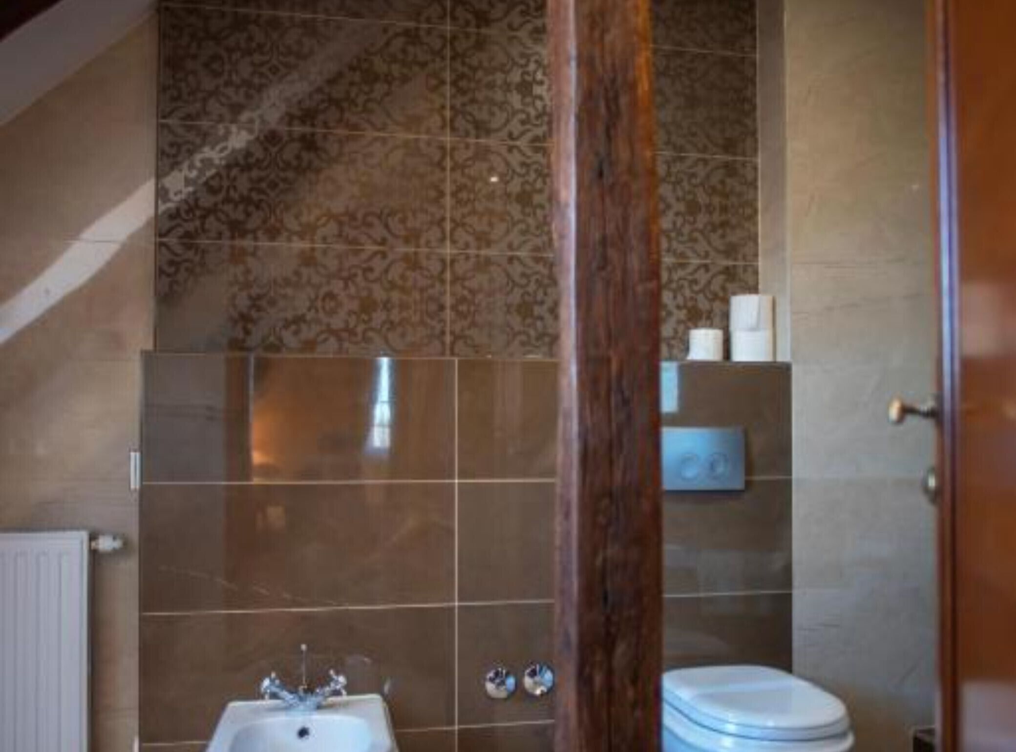 A bathroom with a sink, toilet, and patterned tiles.