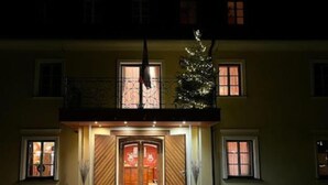 En toetagers bygning med en midterindgang, en balkon med gelænder og et juletræ med lys.