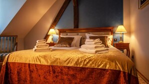 A hotel room with a large bed, two bedside lamps, and a wooden headboard. - Jurjevec Castle - Standard room 6 (Brezane Lekenicke)