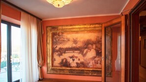 A room with a large framed painting on the wall, a wooden floor, and a door leading to another room. - Jurjevec Castle - Standard room 6 (Brezane Lekenicke)