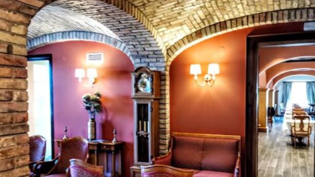 A lobby with a brick archway, a clock, and a seating area with patterned chairs. - Jurjevec Castle - Standard room 6 (Brezane Lekenicke)