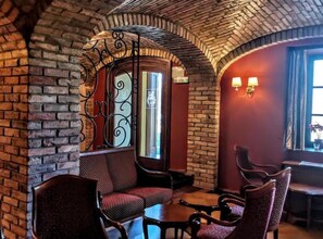 Un intérieur chaleureux avec des murs en briques, un portail en fer forgé et un espace détente avec des chaises et des tables.