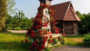 A rustic wooden chapel with a bell tower, surrounded by lush greenery and red flowers. - Jurjevec Castle - Standard room 7 (Brezane Lekenicke)