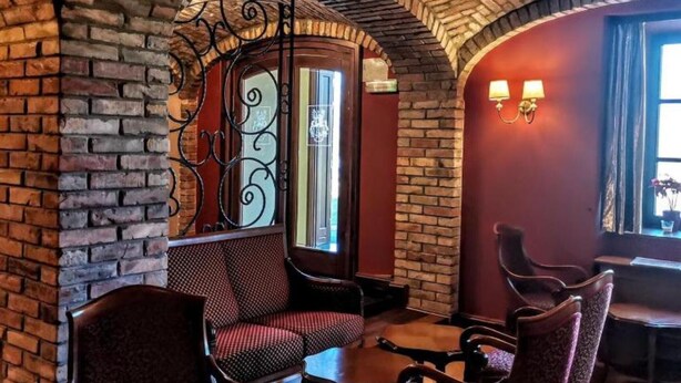 Un intérieur chaleureux avec des murs en briques, un portail en fer forgé et un espace détente avec des chaises et des tables.