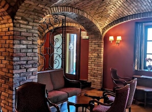 A cozy interior with brick walls, a wrought iron gate, and a seating area with chairs and tables. - Jurjevec Castle - Standard room 9 (Brezane Lekenicke)