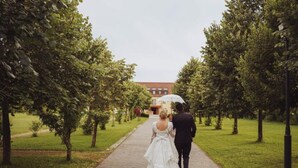 A couple walking down a paved pathway lined with trees, heading towards a building in the background. - Jurjevec Castle - Standard room 11 (Brezane Lekenicke)