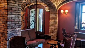 A cozy interior with brick walls, a wrought iron gate, and a seating area with chairs and tables. - Jurjevec Castle - Standard room 11 (Brezane Lekenicke)