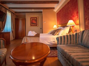 A hotel room with a bed, a sofa, a round wooden table, and a painting on the wall. - Jurjevec Castle - Standard room 12 (Brezane Lekenicke)