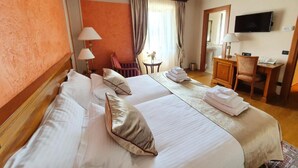 Een hotelkamer met twee bedden, een bureau, een stoel, een televisie en een raam met gordijnen.