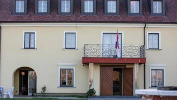 En bygning med en symmetrisk facade, mange vinduer og en central indgang med et flag.
