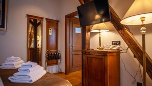 Ein Hotelzimmer mit einem Bett, einem an der Wand montierten Fernseher, einem Schreibtisch mit einer Lampe und einem Kleiderständer.