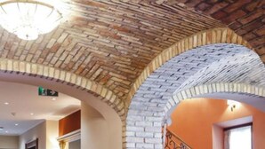 Ein Zimmer mit Ziegeldecke, Bogenportal und einer Kandelaber.