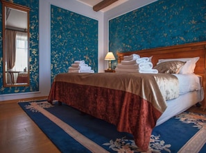 Une chambre d’hôtel avec un grand lit, une tête de lit en bois, une table de chevet avec une lampe et un miroir.