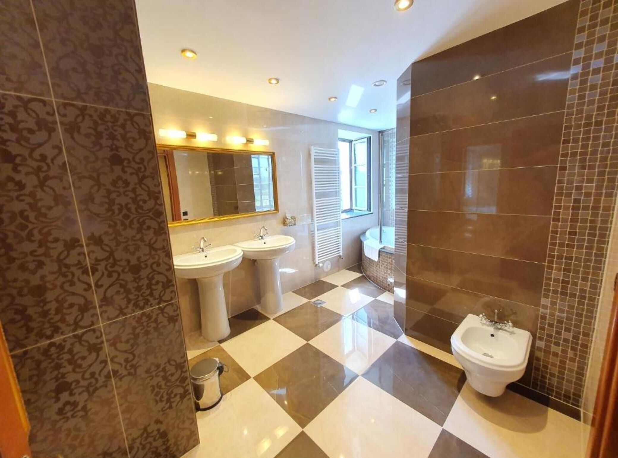 Une salle de bain moderne avec deux lavabos, un bidet et un grand miroir.