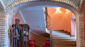 A grand staircase with a wooden finish and a red velvet chair in the foreground. - Jurjevec Castle - Standard room 18 (Brezane Lekenicke)