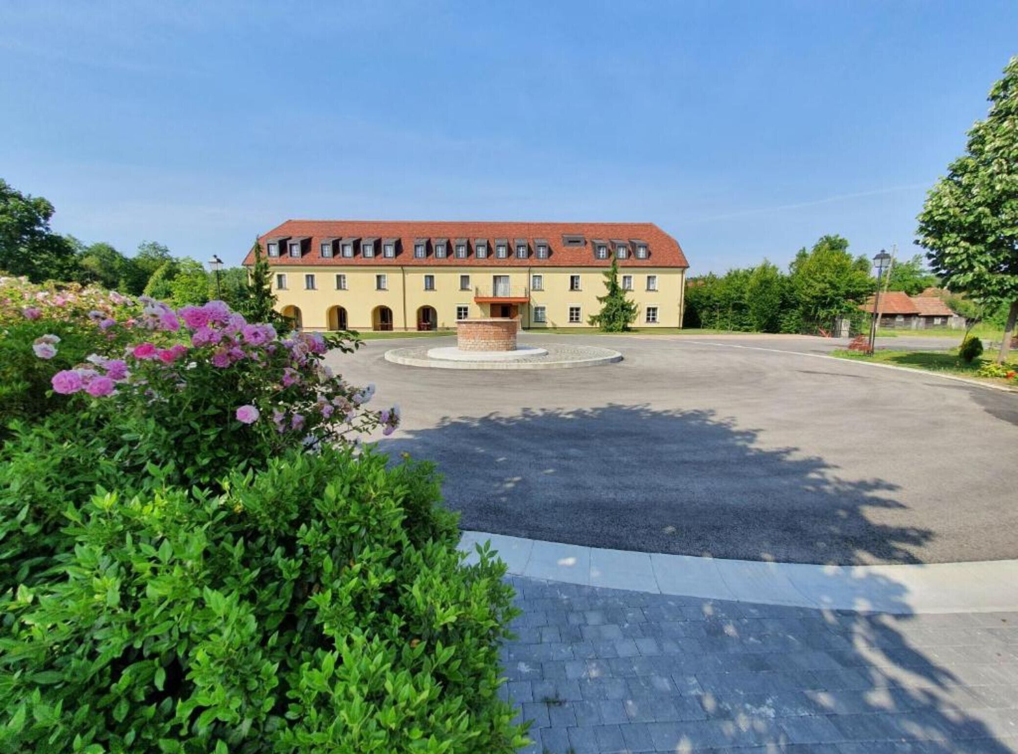 Ein großes Gebäude mit einem zentralen Innenhof, umgeben von üppiger Vegetation und blühenden Pflanzen.