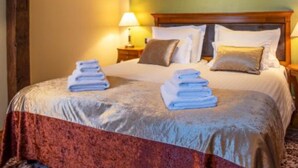 Une chambre d’hôtel avec un lit, des oreillers, une table de chevet, une lampe et des serviettes pliées posées sur le lit.