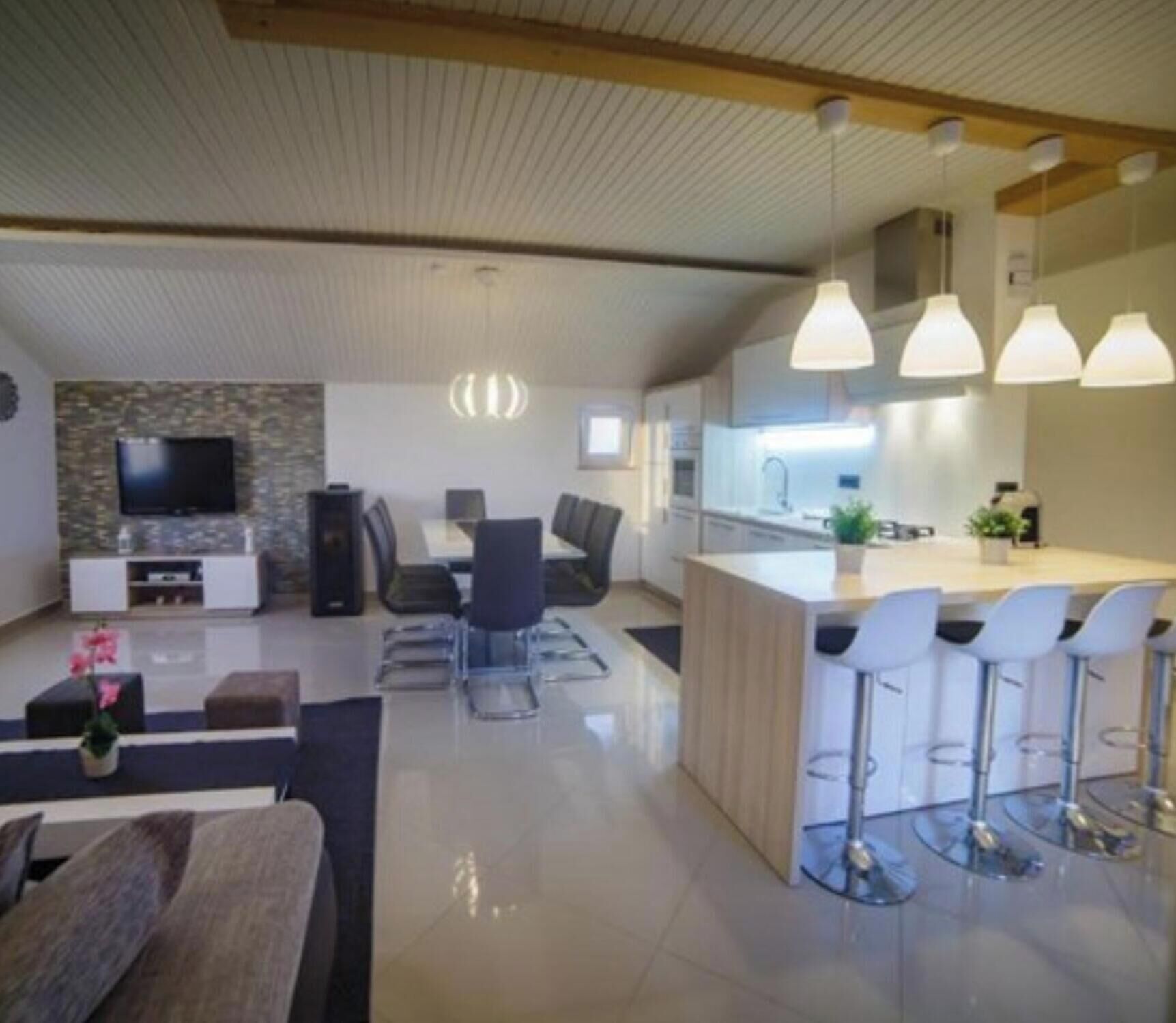 A modern kitchen with a central island, bar stools, and pendant lighting.