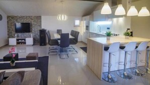 A modern kitchen with a central island, bar stools, and pendant lighting. - Apartments Foric - Two bedroom apartment (1) (Rab)