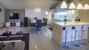 Cozinha moderna com ilha central, banquetas e iluminação pendente.