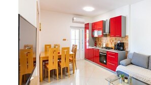 Uma cozinha moderna com armários vermelhos, uma área de jantar com cadeiras de madeira e uma mesa de centro de vidro.
