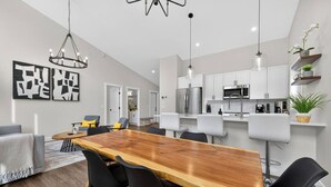 A modern kitchen with white cabinets, stainless steel appliances, and a hanging light fixture. - Basecamp | Beach Access | Sports Court | Foosball (Invermere)