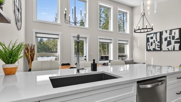 A modern kitchen with a large island, white cabinetry, and a stainless steel dishwasher. - Basecamp | Beach Access | Sports Court | Foosball (Invermere)