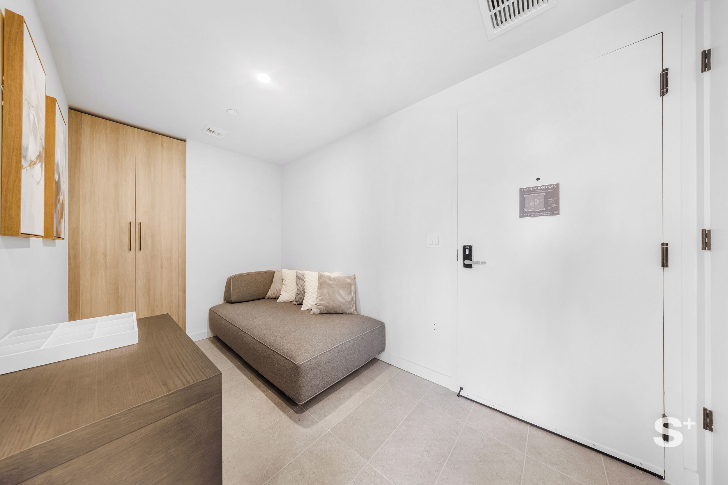 A modern room with a sofa, a wooden cabinet, and a white door.