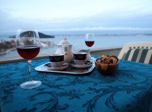 Une table sur laquelle sont disposés un plateau de tasses à thé, une théière et un bol de noix, le tout placé devant un paysage pittoresque.