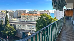 A balcony with a view of a cityscape, including buildings and a road with a motorcycle. - Magnificent Apartment in park residence in 5 min from the seaside (Nice)