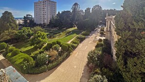A landscaped garden with a central pathway, a statue, and a tall building in the background. - Magnificent Apartment in park residence in 5 min from the seaside (Nice)