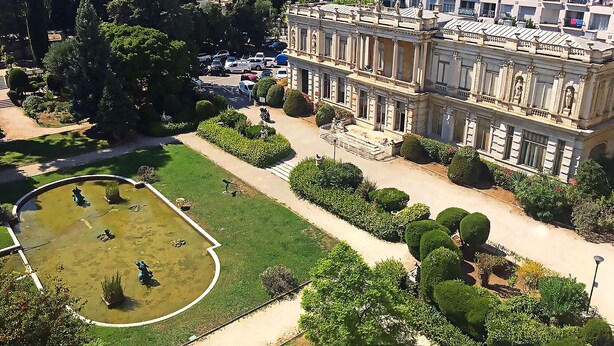 A large, historic building with classical architecture, surrounded by well-maintained gardens and a small pond. - Magnificent Apartment in park residence in 5 min from the seaside (Nice)