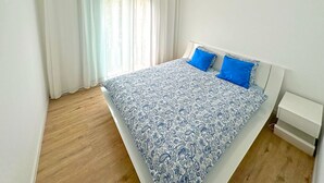A bedroom with a bed, white curtains, a ceiling fan, and an air conditioning unit. - Magnificent Apartment in park residence in 5 min from the seaside (Nice)