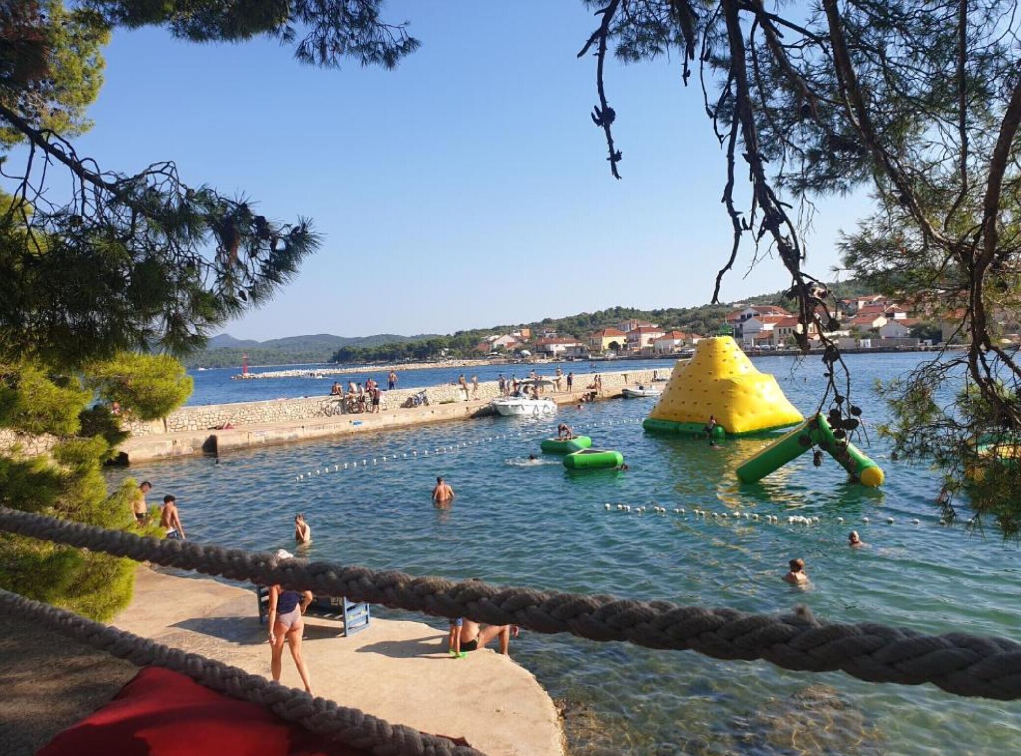 Ett kustområde med fri utsikt över havet, en sandstrand och en klippig pir.