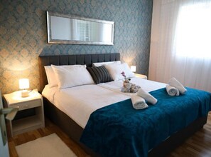 A neatly made bed with white linens, a blue bedspread, and two rolled towels on the side. - Franov Butique Residence - Two bedroom apartment with sea view (Isabell) (Kali)