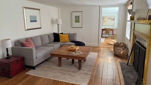 Una sala de estar con sofá gris, mesa de centro de madera y chimenea.