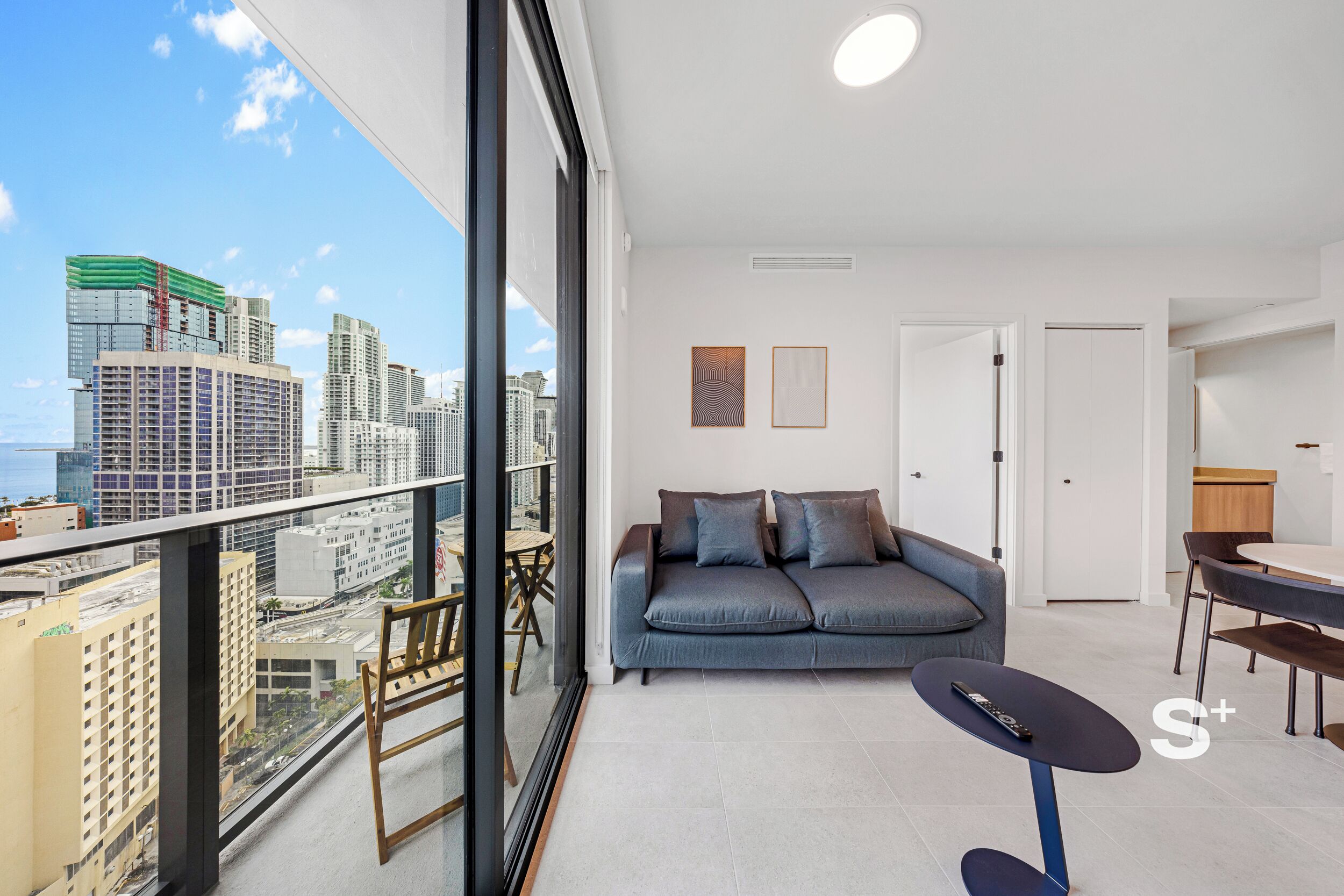 Een moderne woonkamer met een bank, een bijzettafeltje en een balkon met uitzicht over de stad.