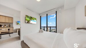 A modern hotel room with a large bed, a desk, and a view of the beach. - High-Rise Miami Condo - Sea View (Miami)