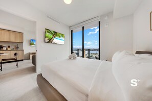 Habitación de hotel moderna con una cama grande, un escritorio y vista a la playa.